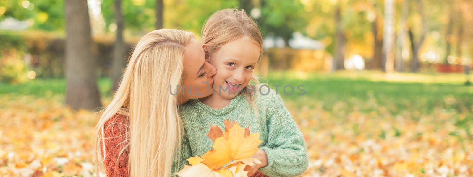 Woman and girl holding autumn yellow leaves by okskukuruza