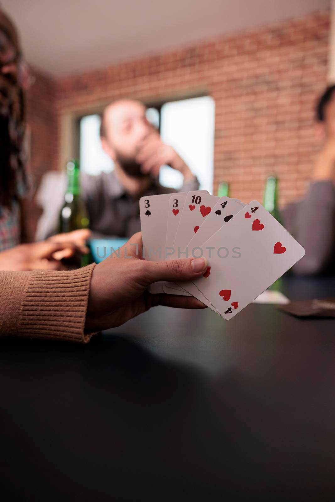 Close up shot of caucasian woman hand holding card games while enjoying fun leisure activity with friends. by DCStudio