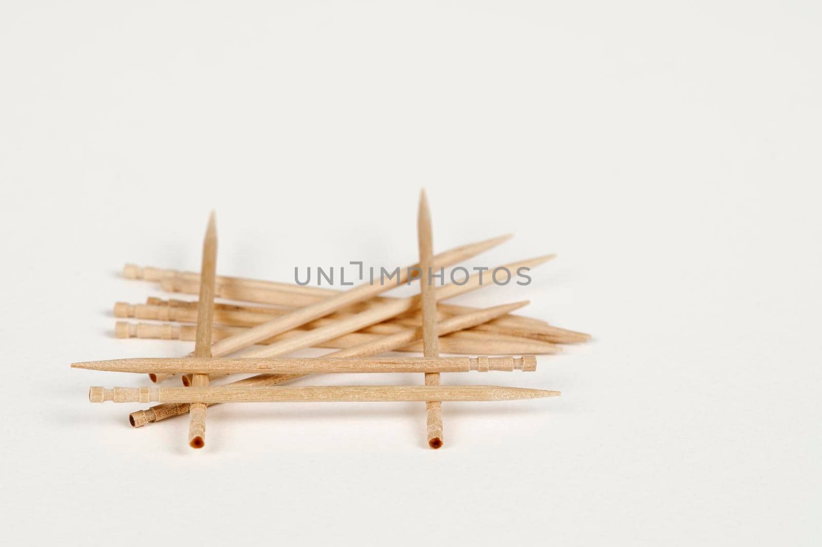 Closeup view of a pile of wooden toothpicks on a white bsckground