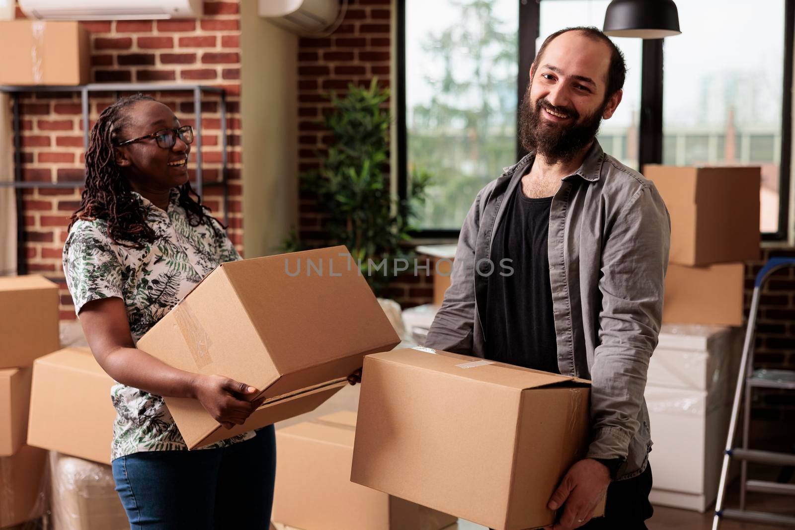 Portrait of diverse life partners posing with boxes on moving day by DCStudio
