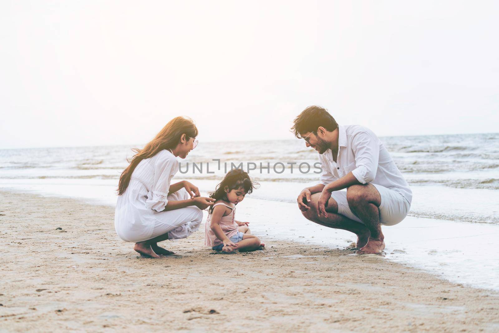 Happy family of father, mother and kids goes vacation on a tropical sand beach in summer.