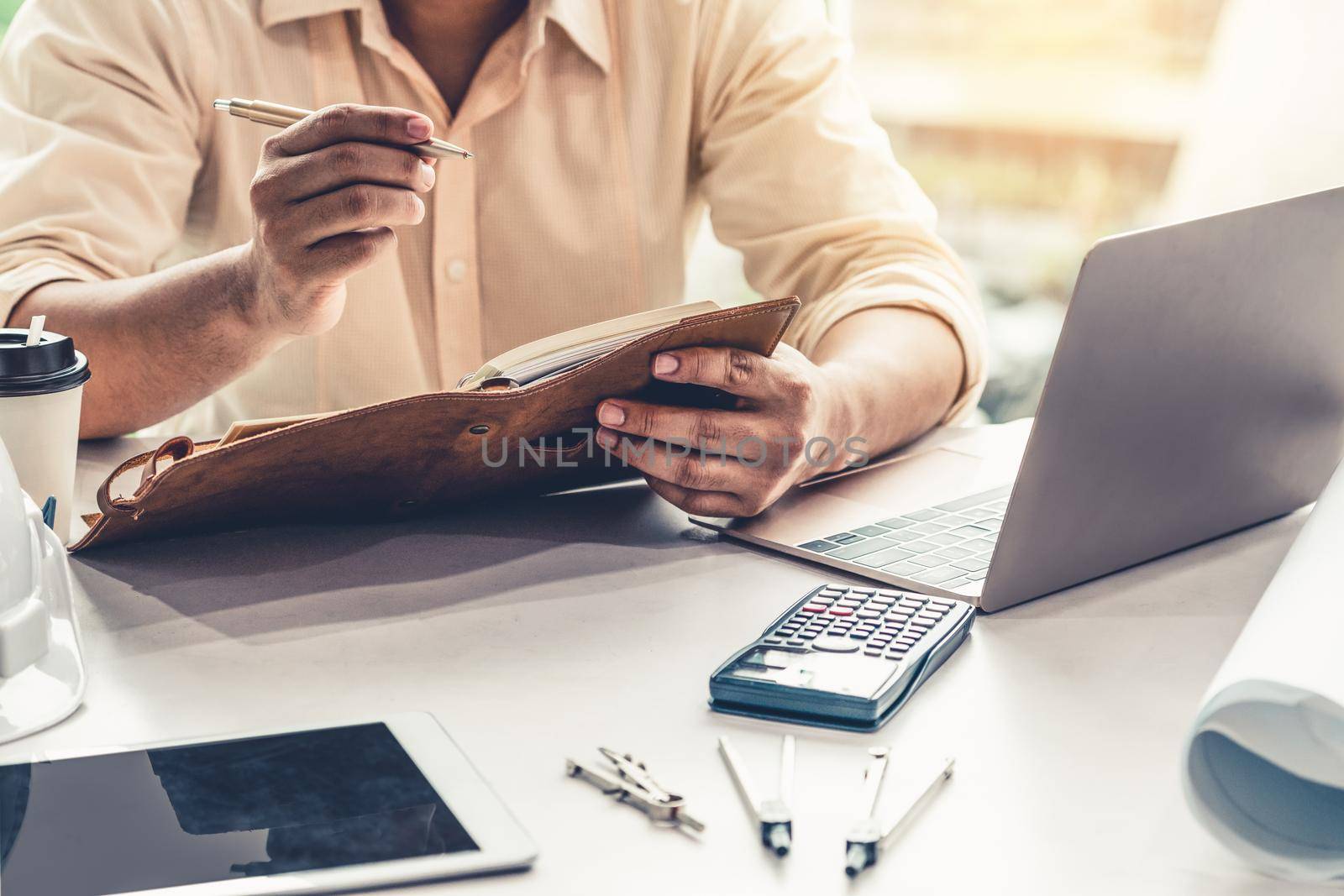 Young man architect or engineer working at desk. by biancoblue