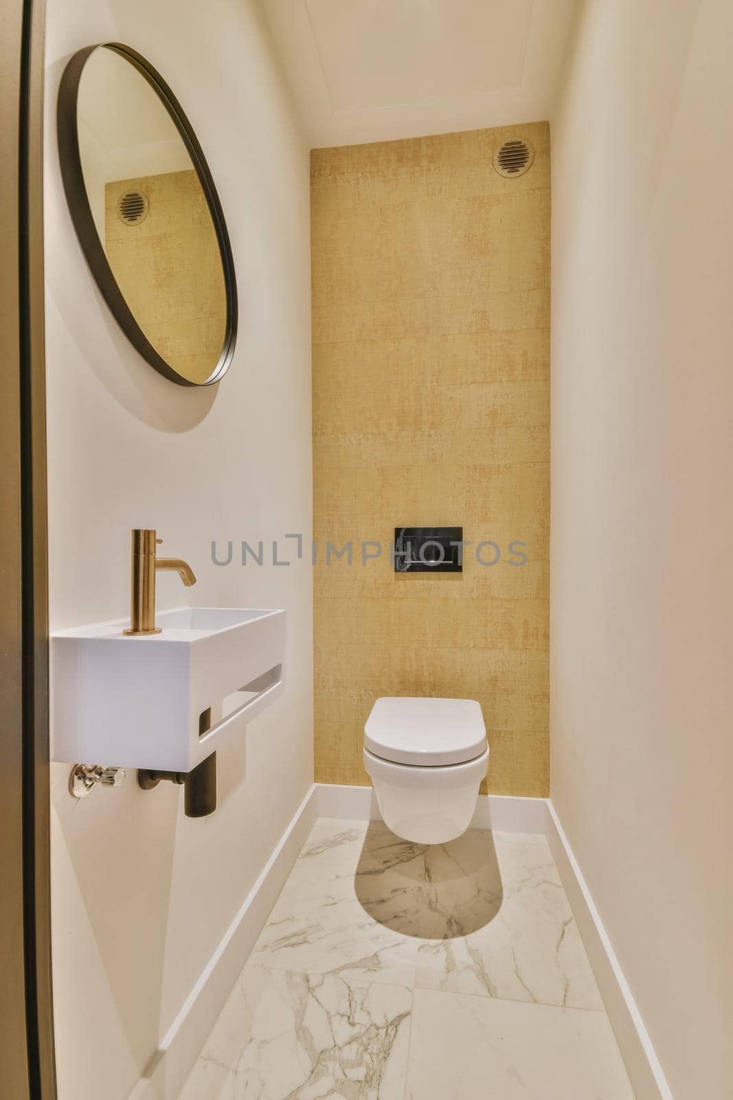 Wall hung toilet and small sink in corner in lavatory room with beige tile