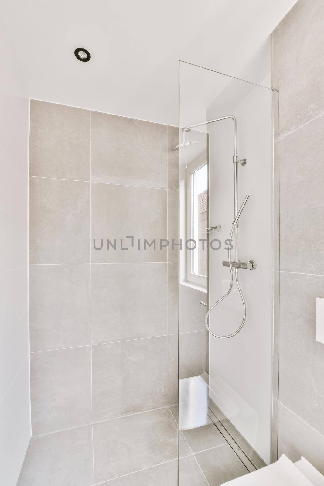 Cozy shower cabinet with glass door and grey tiled walls