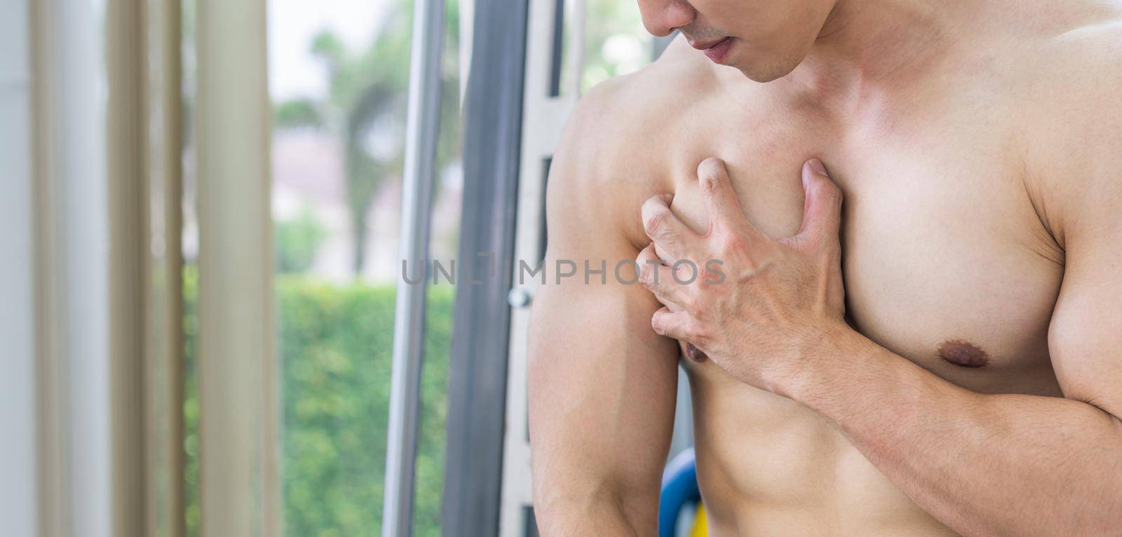 Muscular man touching his chest in fitness center. Bodybuilding concept.