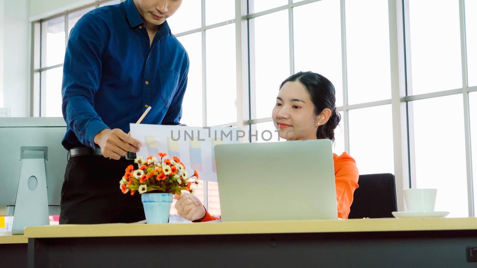 Two business people talk project strategy at office meeting room. Businessman discuss project planning with colleague at modern workplace while having conversation and advice on financial data report.