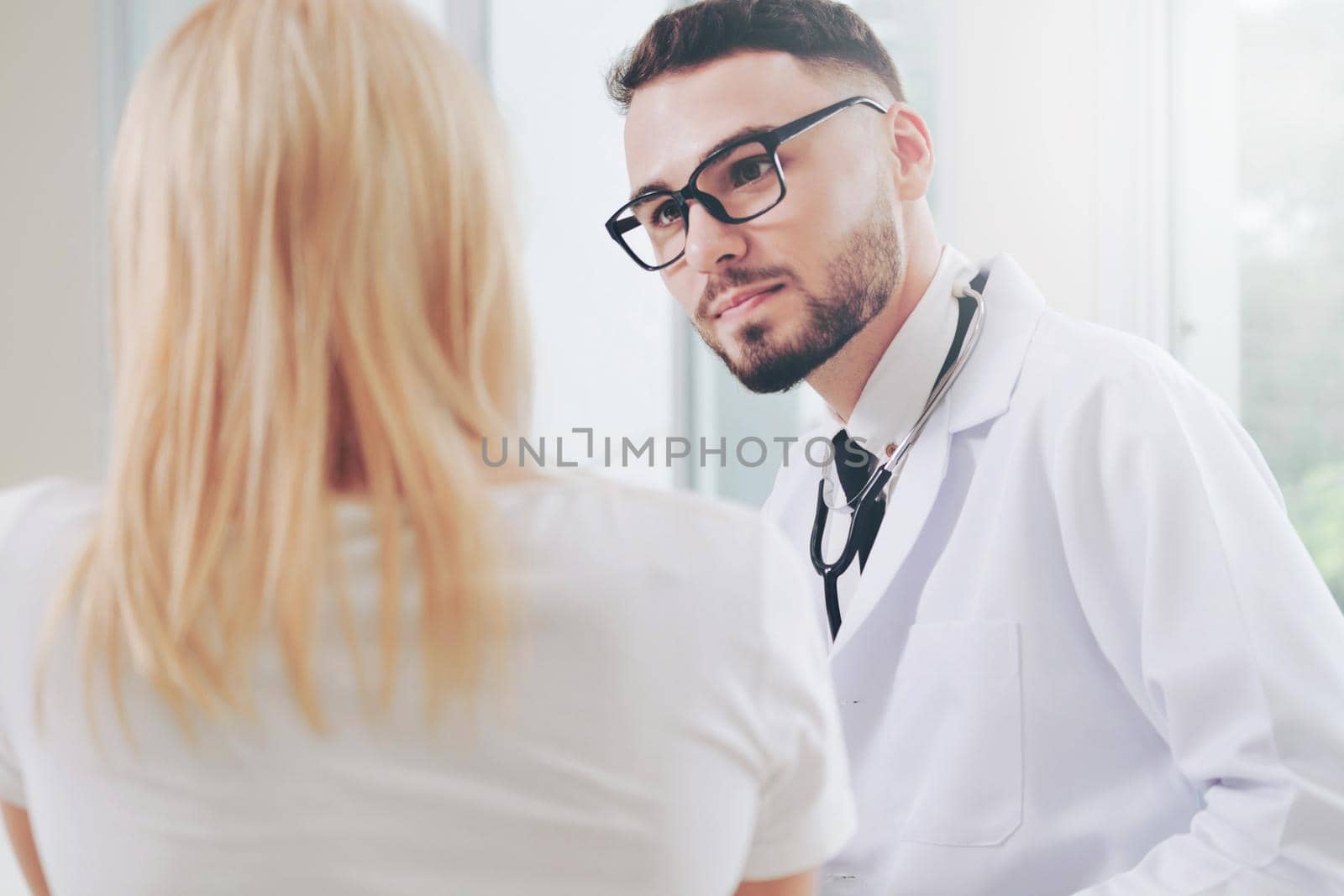 Male doctor is talking with female patient in hospital office. Healthcare and medical service.