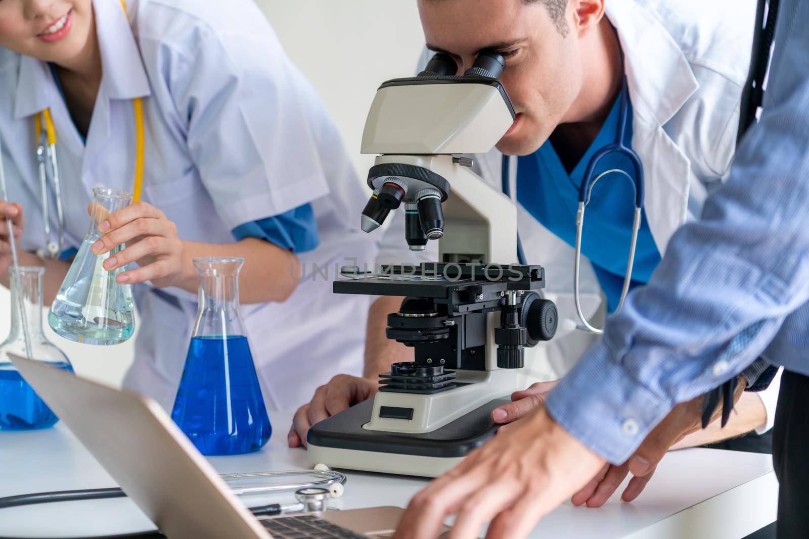 Group of scientists wearing lab coat working in laboratory while examining biochemistry sample in test tube and scientific instruments. Science technology research and development study concept.