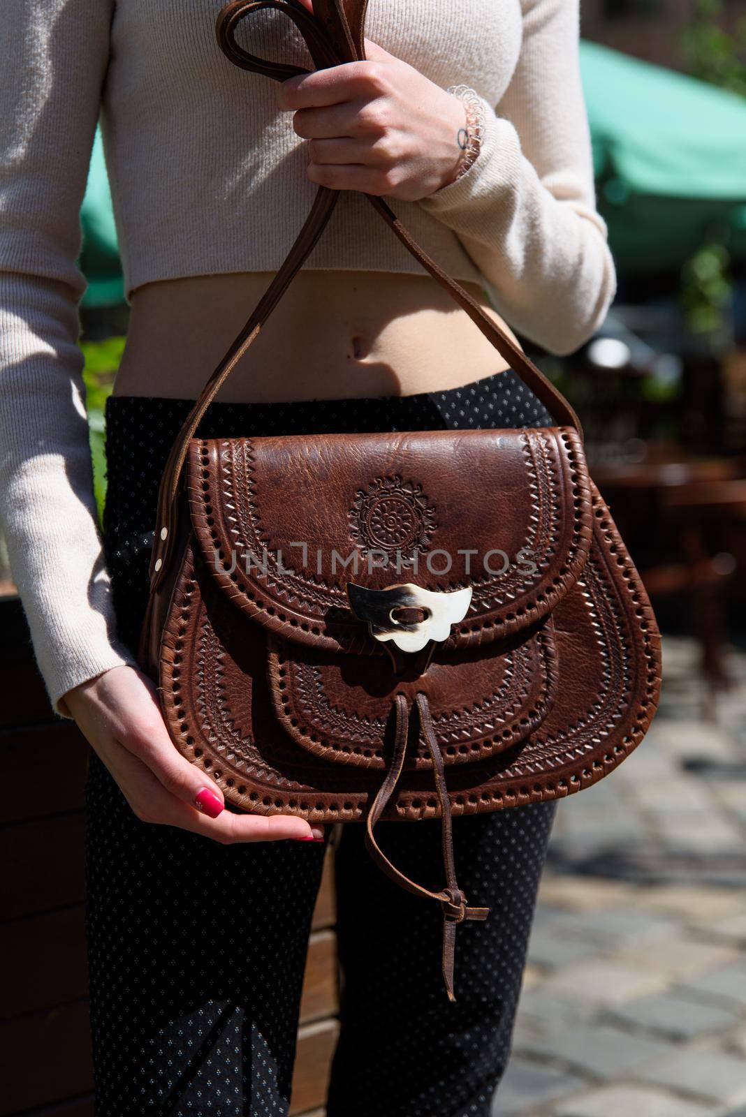 small brown women's leather bag with a carved pattern. street photo