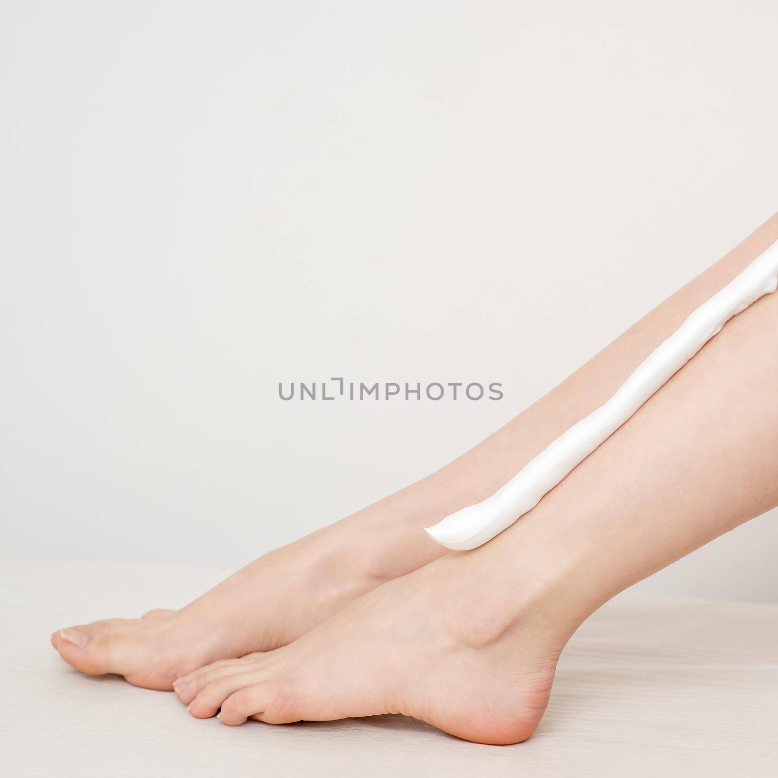 Female nice long slim bare legs with shaving foam on white background