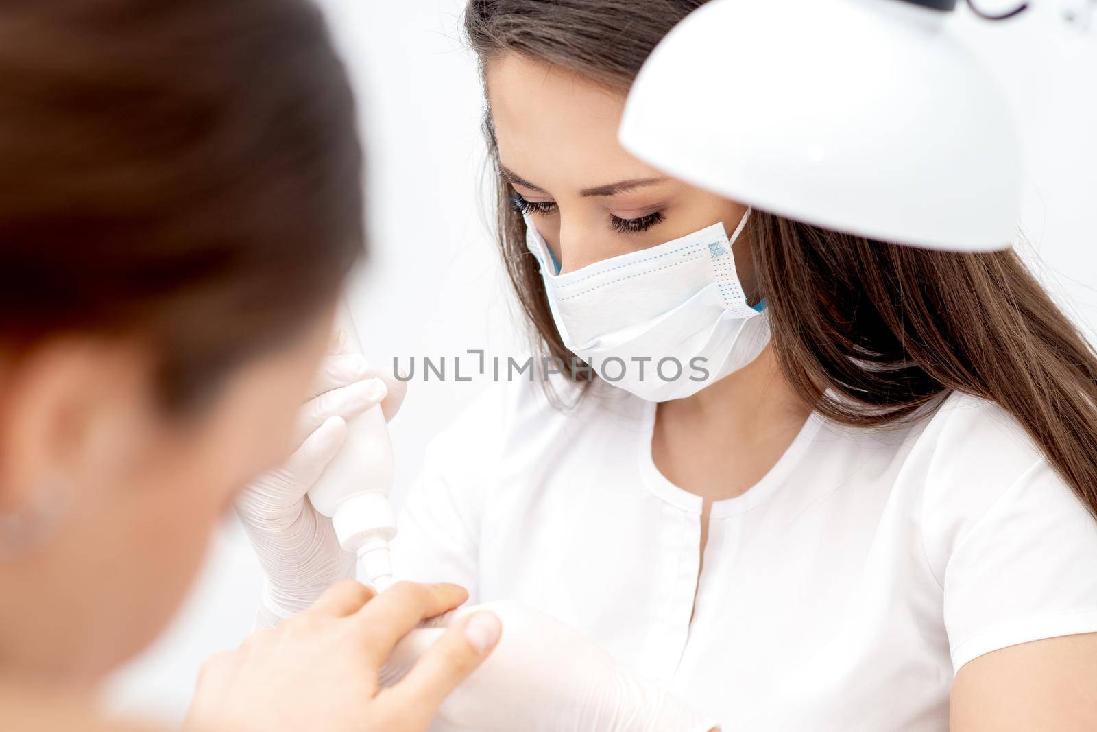 Manicurist pours oil on nails of woman by okskukuruza