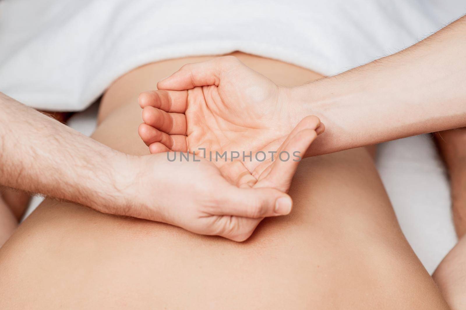Palms of hands on human back by massager during hands show yin and yang.