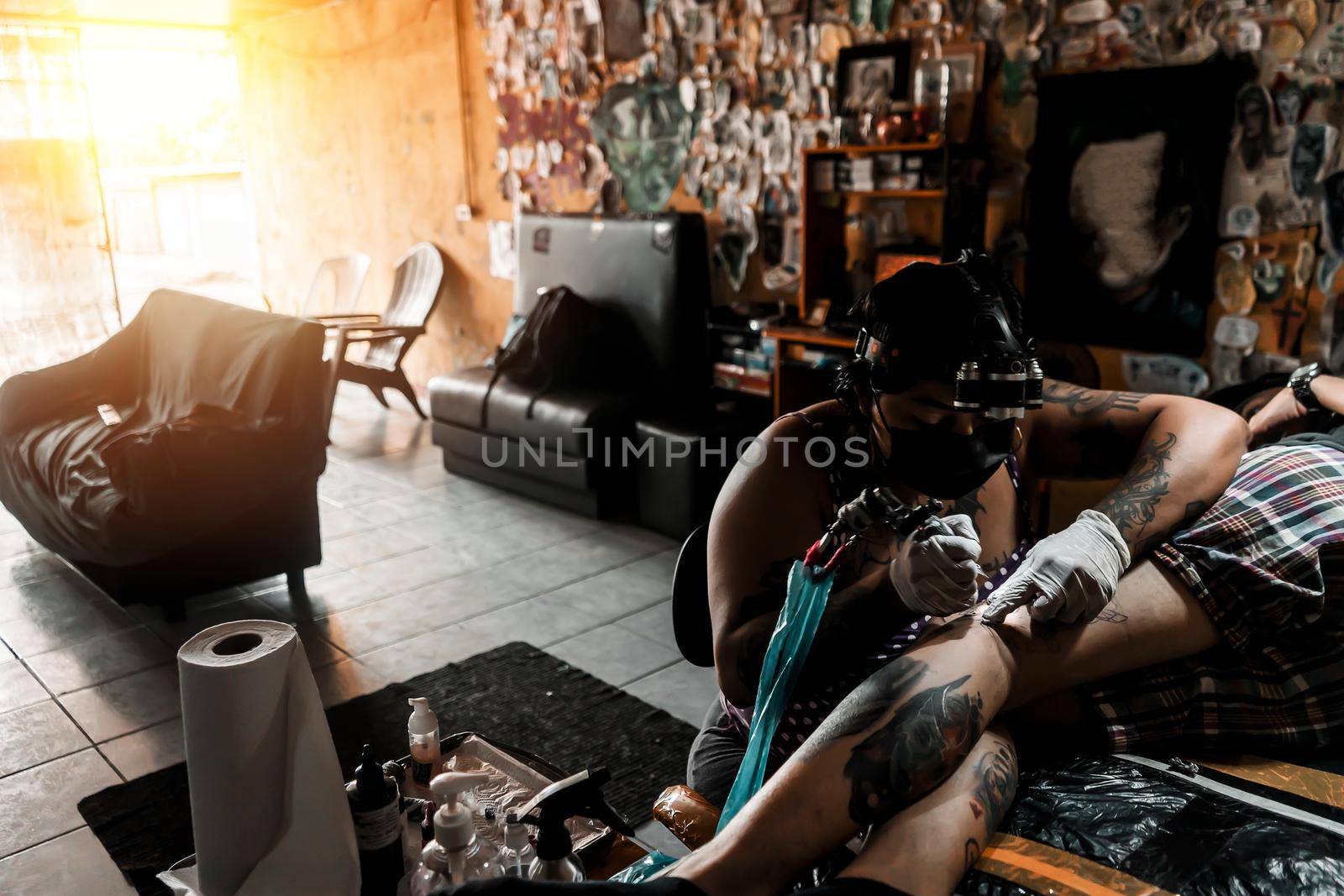 Latina tattoo artist working on an art on a client's leg in a studio in Managua Nicaragua