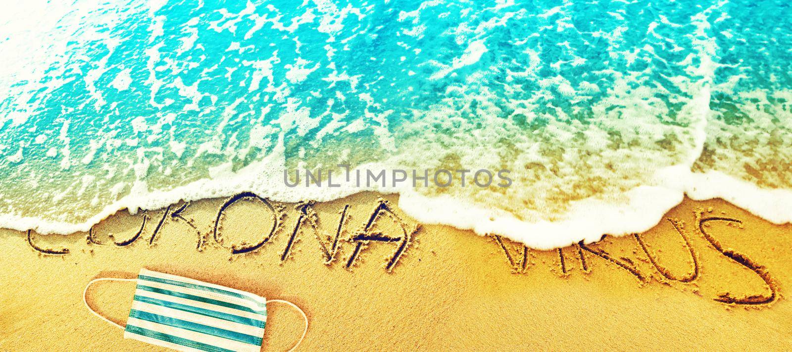 Corona virus written in the sand on vacation by Taut