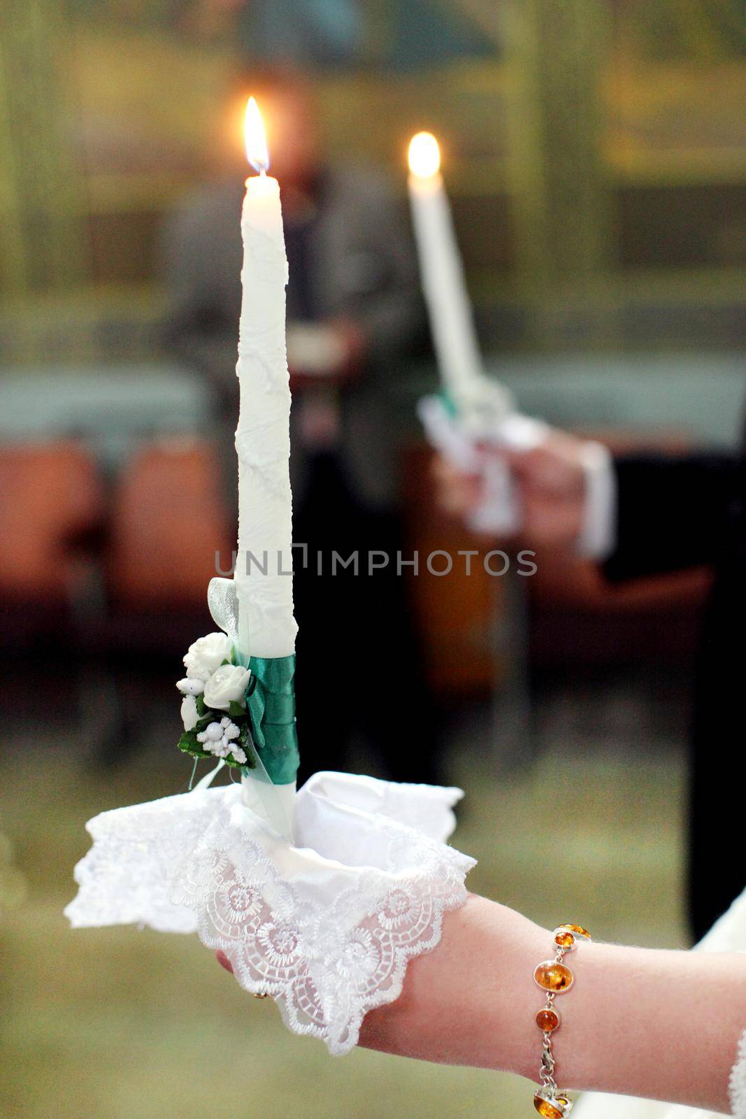 The bride, groom holds in hands wedding candle. Burn candle. Spiritual couple holding candles during wedding ceremony in christian church. close up.