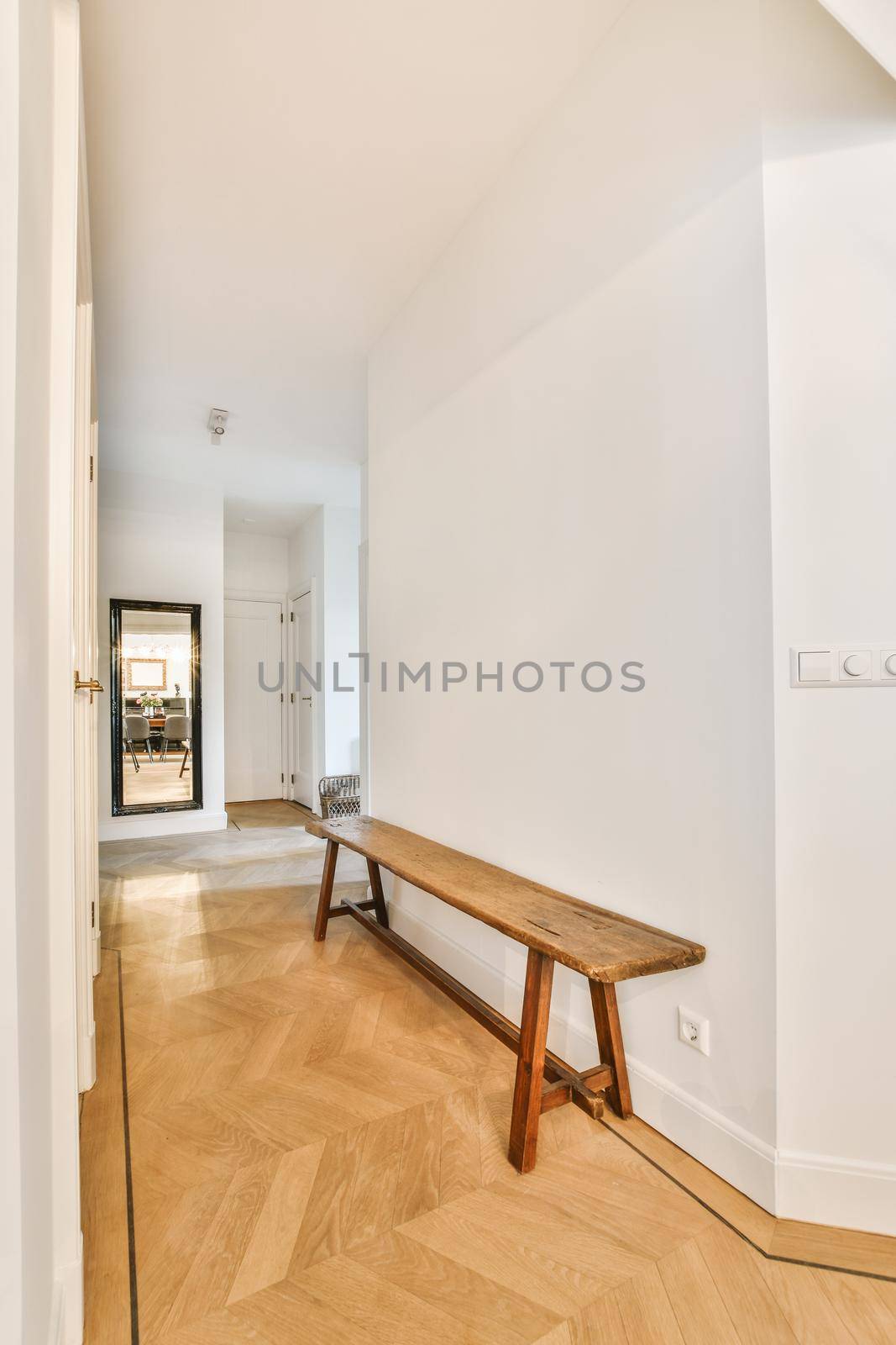 Light narrow hallway with many doors in white walls and glowing lamp over lumber floor