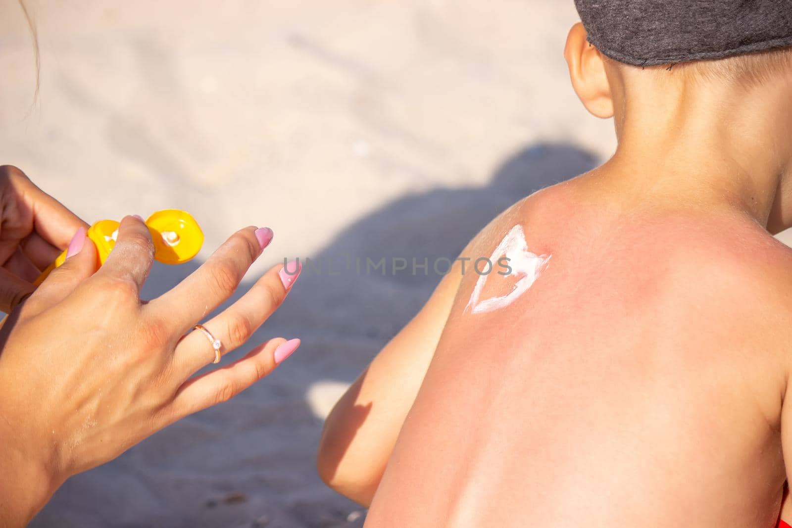 Mom puts sunscreen on Sin's back in the shape of a heart. selective focus