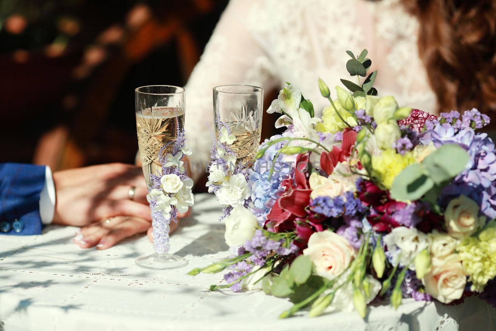 Wedding decoration in the style of boho, floral arrangement, decorated table in the garden. Against the background of the bride and groom embracing.