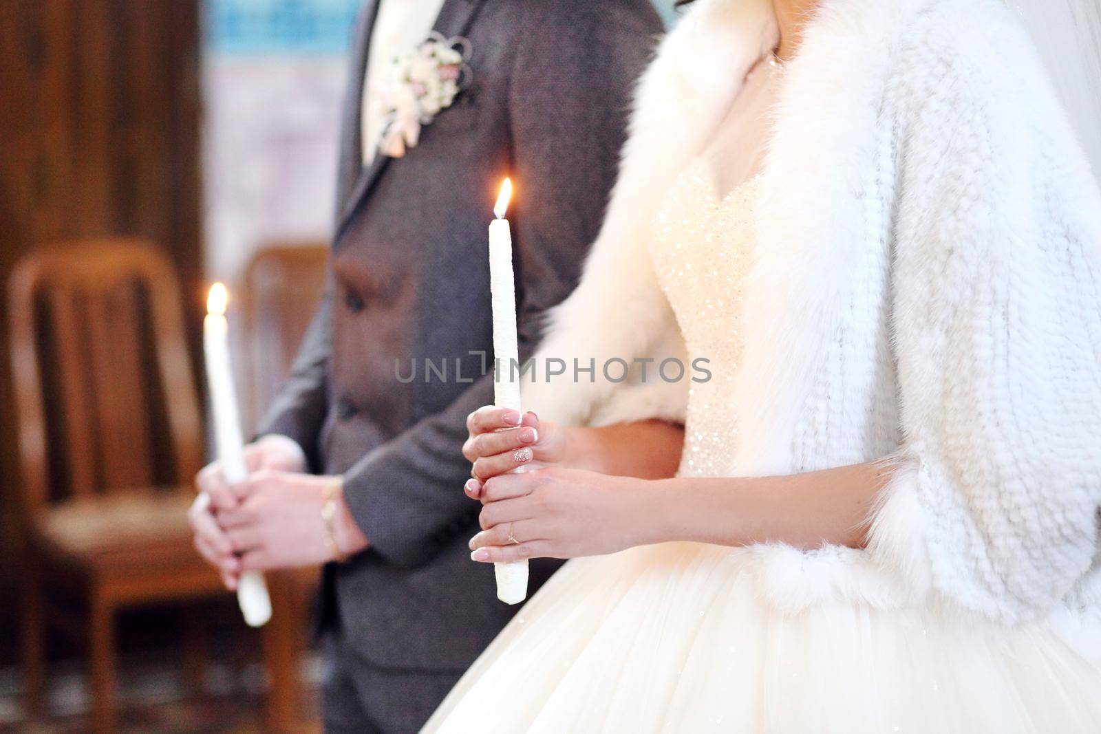 The bride, groom holds in hands wedding candle. Burn candle. Spiritual couple holding candles during wedding ceremony in christian church. close up.