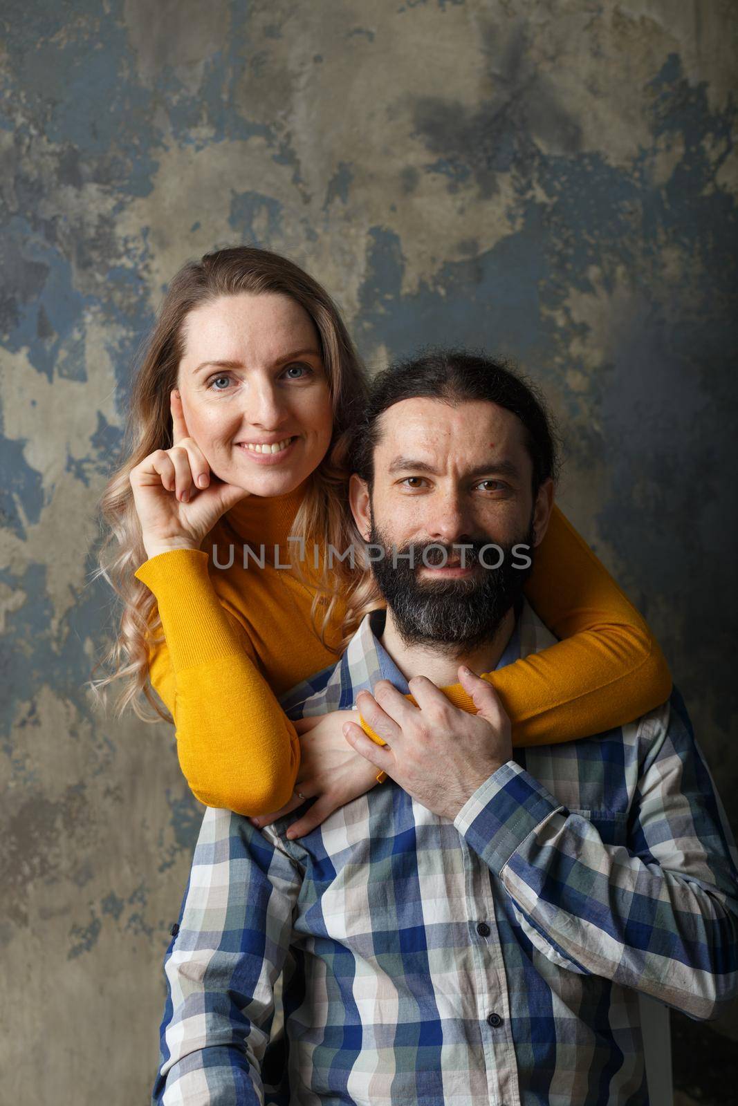 Love and relationship concept. Happy adult couple hugging, smiling wide and looking at camera, standing together on blue abstract background
