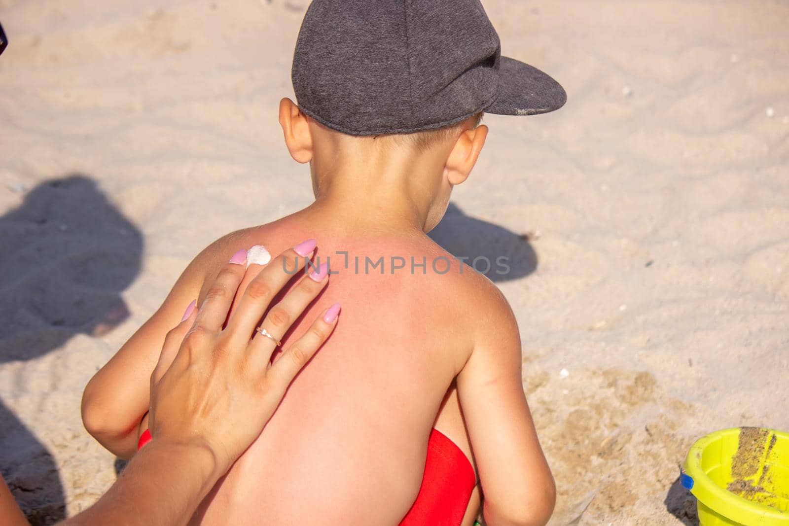 Mom puts sunscreen on Sin's back in the shape of a heart. selective focus