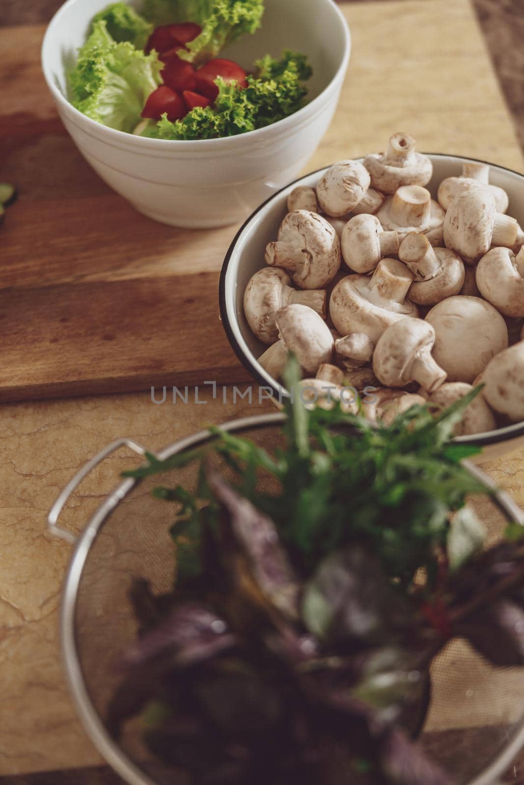 Bowls with basil mushrooms and green salad on the background of the table by Yaroslav_astakhov