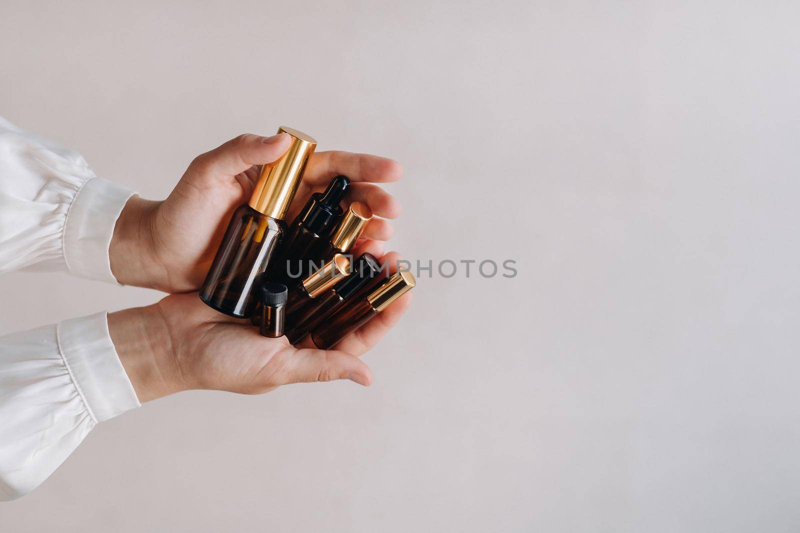 Close-up of female hands holding many bottles of essential oil. Aromatherapy.