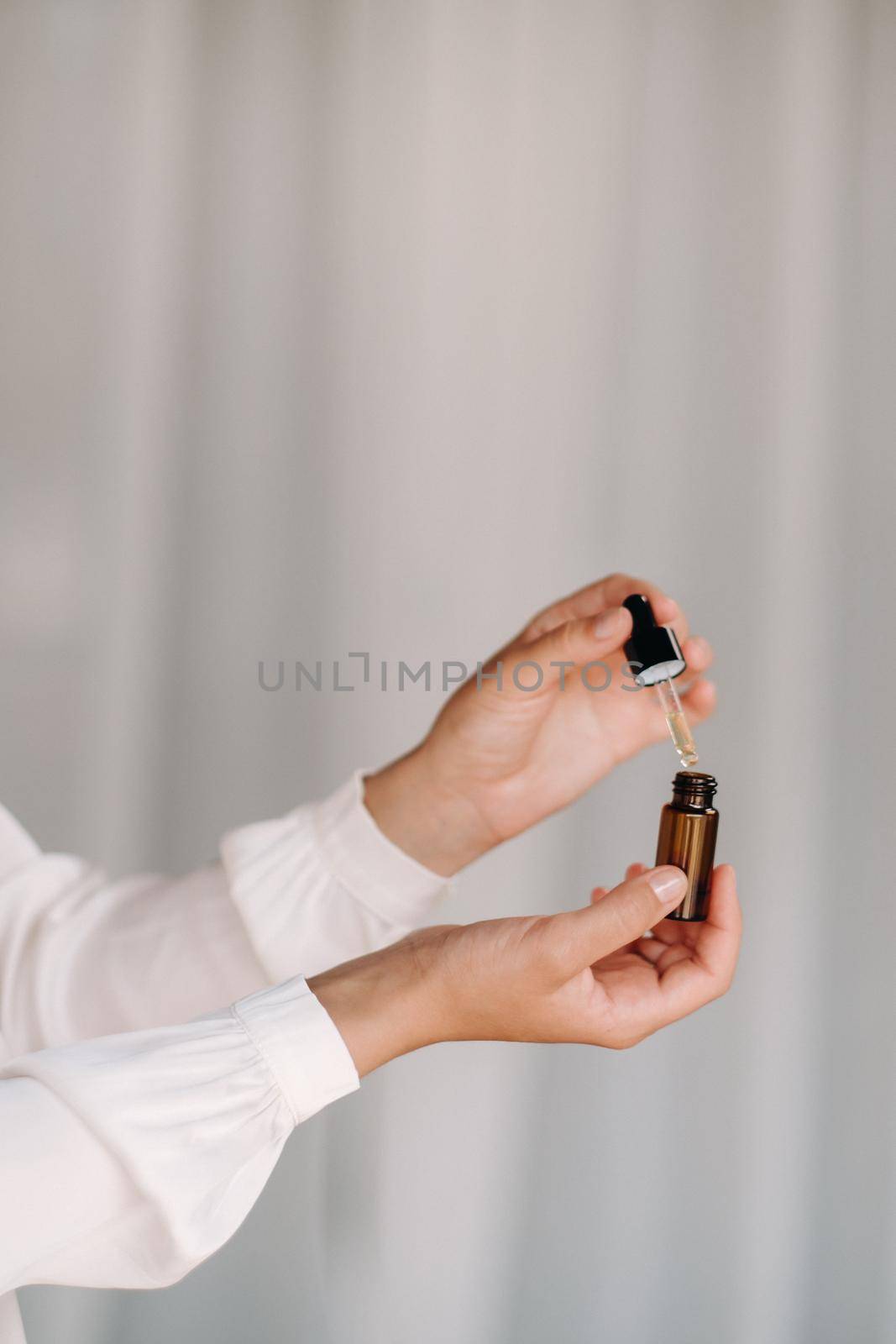 Close-up of female hands holding a bottle of essential oil, Aromatherapy.