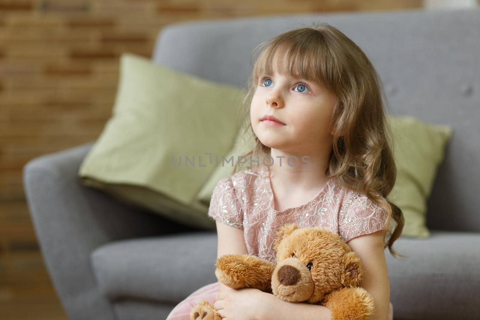 Adorable little girl with teddy bear looking at camera at home, smiling preschool pretty child with beautiful happy face posing alone on sofa, cute positive cheerful kid headshot portrait