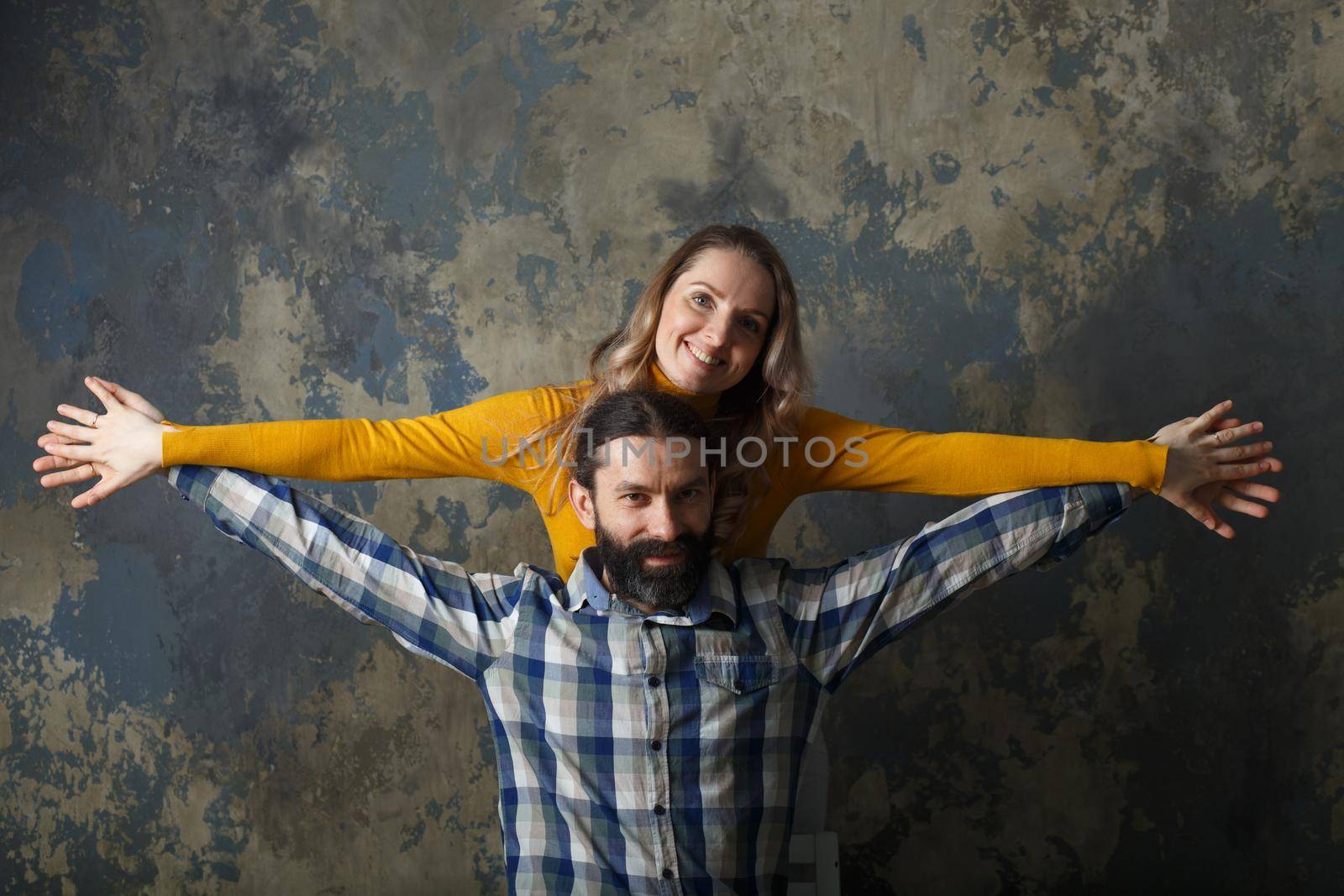 Love and relationship concept. Happy adult couple hugging, smiling wide and looking at camera, standing together on blue abstract background