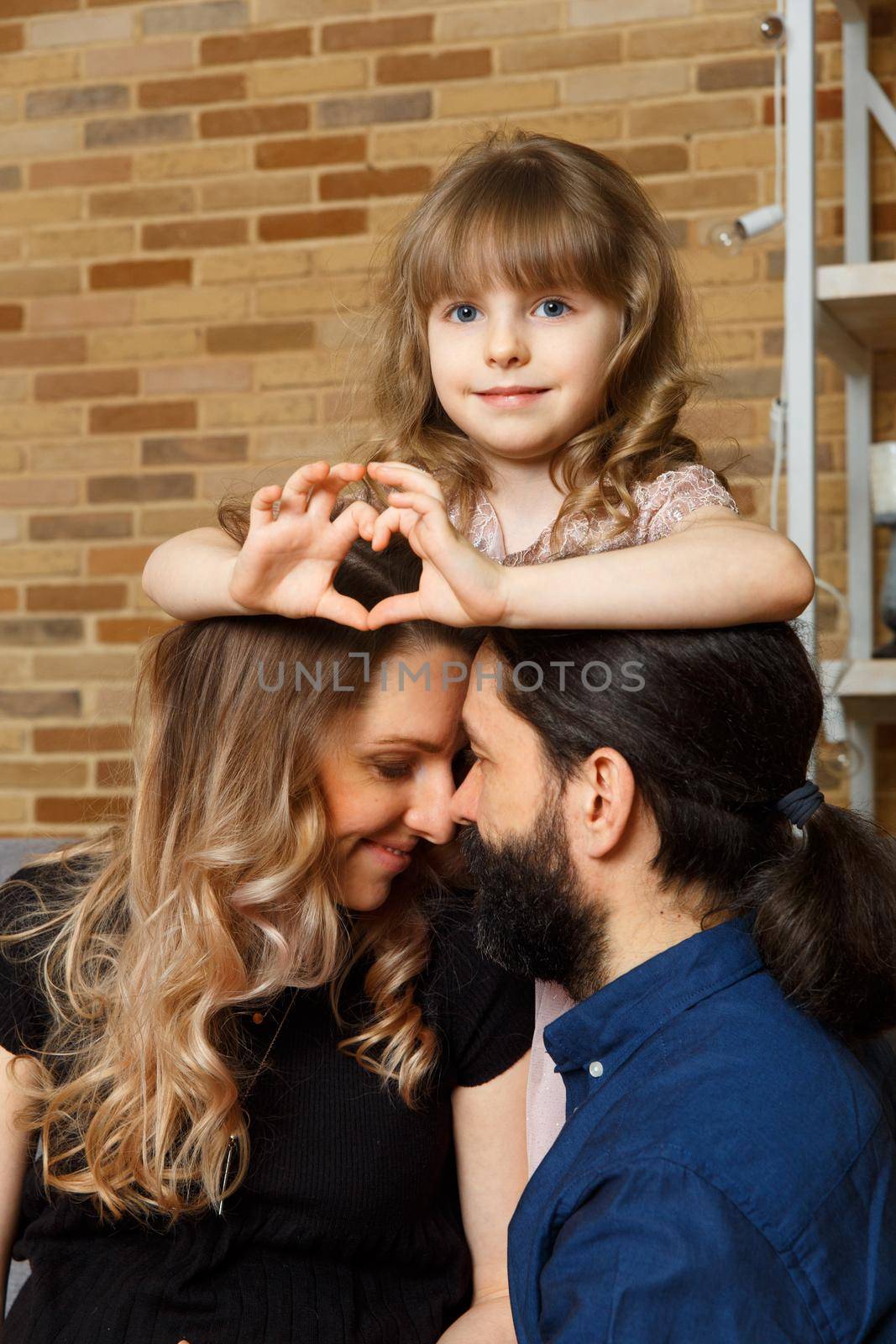 Happy young father, mother and daughter sit on wicker sofa at home. by BY-_-BY