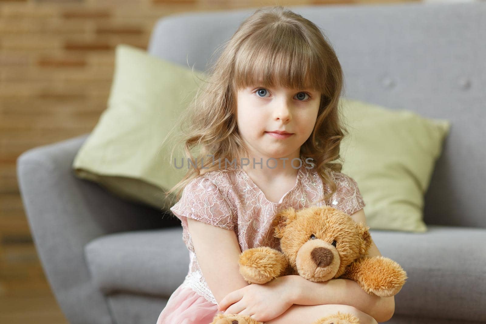 Adorable little girl with teddy bear looking at camera at home, smiling preschool pretty child with beautiful happy face posing alone on sofa, cute positive cheerful kid headshot portrait