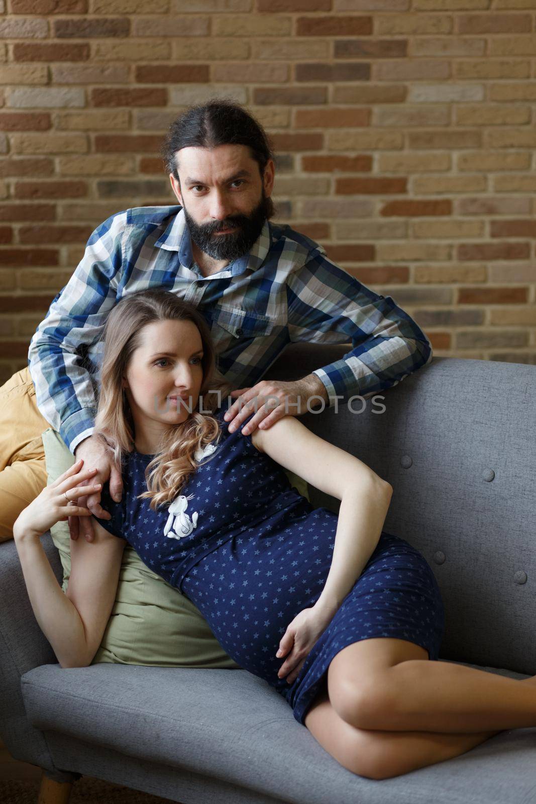 An adult couple in love waiting for a child. A man and his pregnant wife are playing on a sofa at home