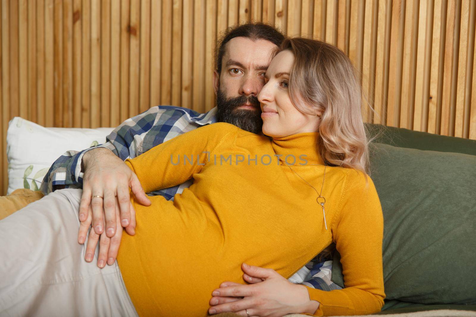 An adult couple in love waiting for a child. A man and his pregnant wife are basking in a bed in the bedroom