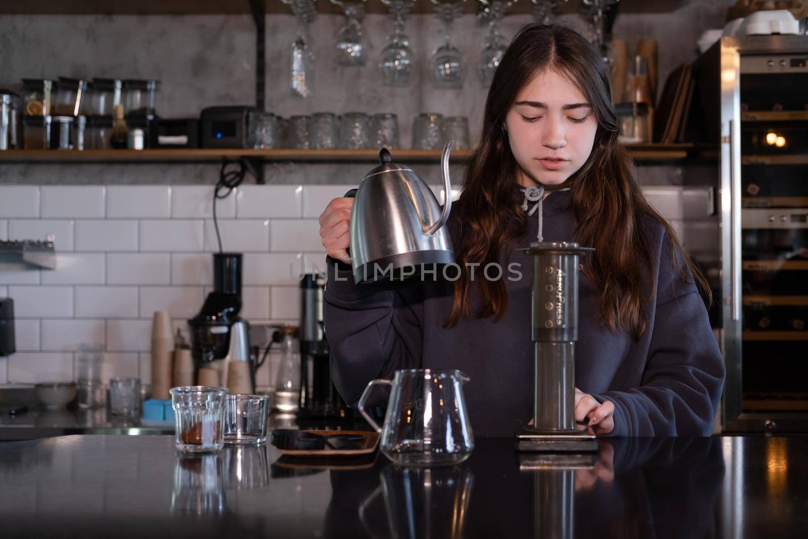 pretty brunette girl making aeropress coffee in modern coffee shop.