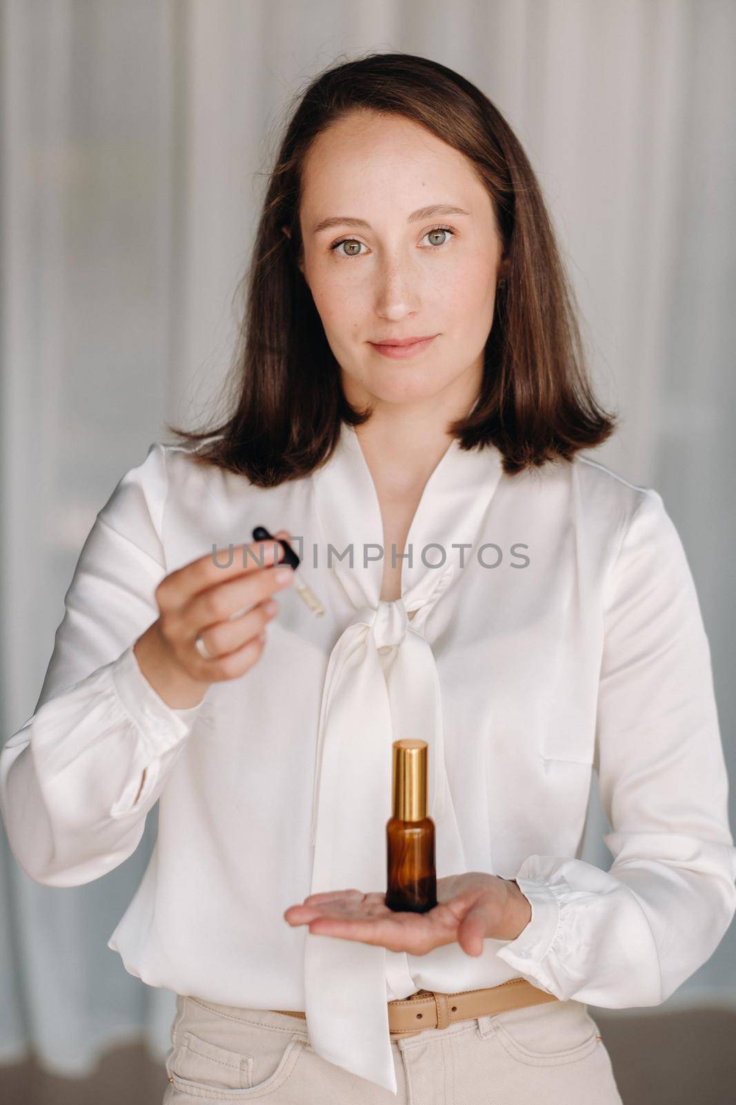 A woman in a white blouse holding a bottle of essential oil, aromatherapy by Lobachad