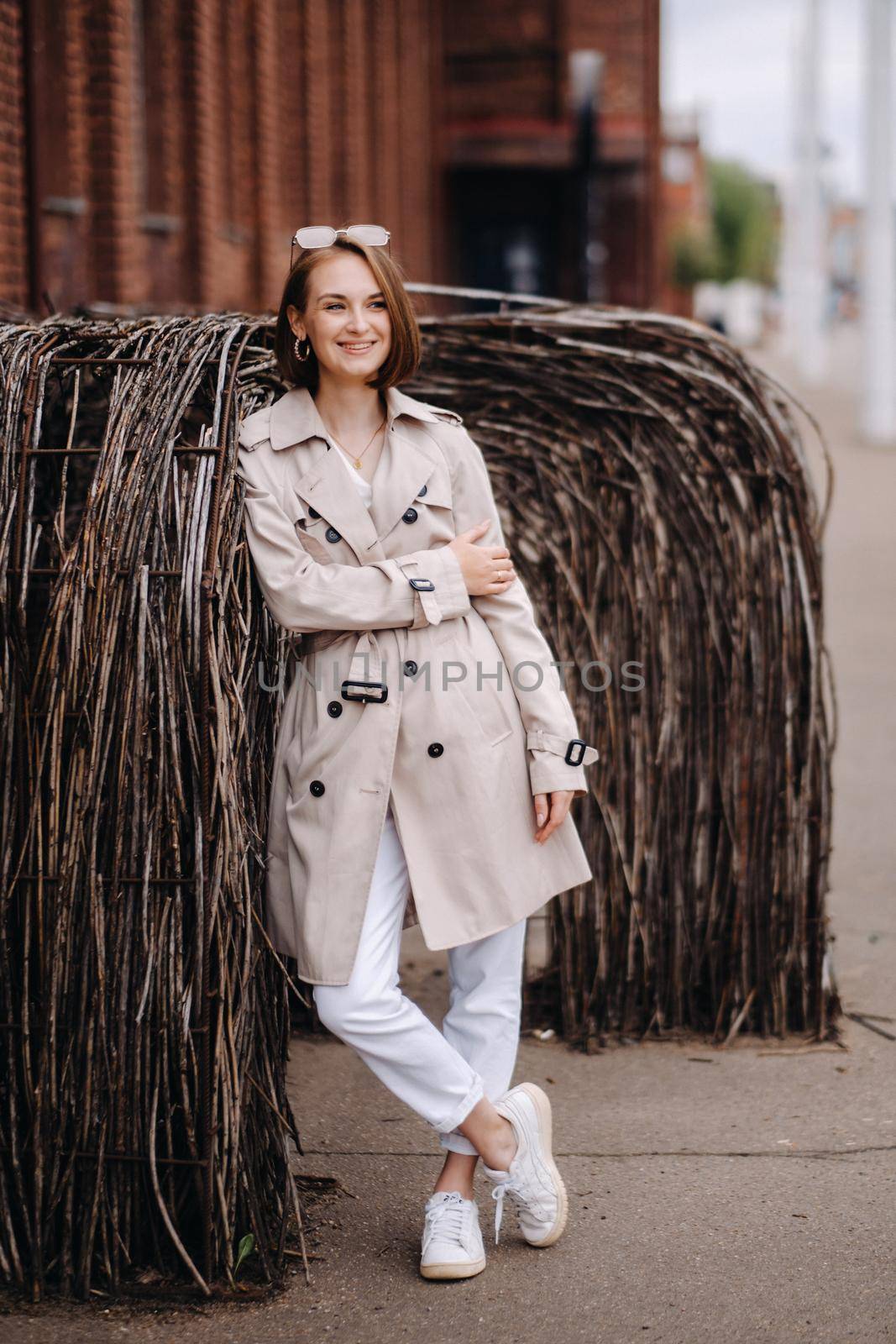 A happy stylish girl in a gray coat walks around the city by Lobachad