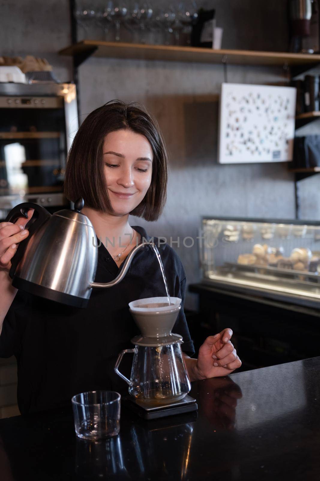 charming brunette woman barista making filter coffee in coffee shop. brewing coffee in cafe by oliavesna