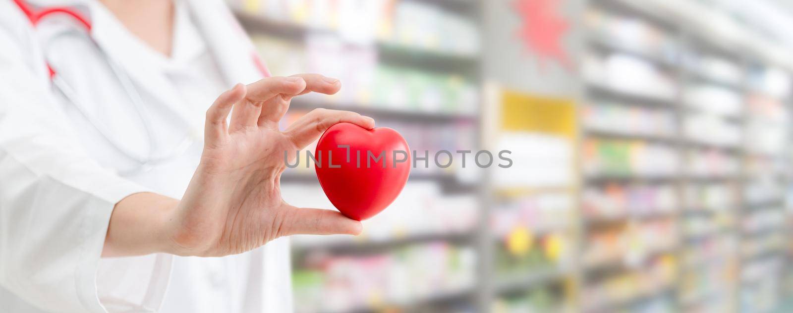 Doctor holding a red heart at hospital office. by biancoblue