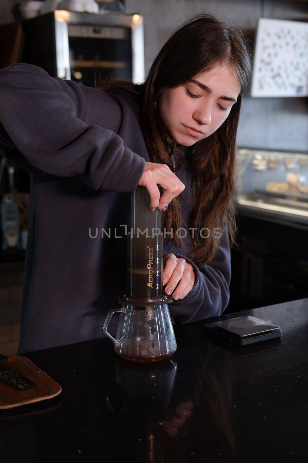 pretty brunette girl making aeropress coffee in modern coffee shop by oliavesna