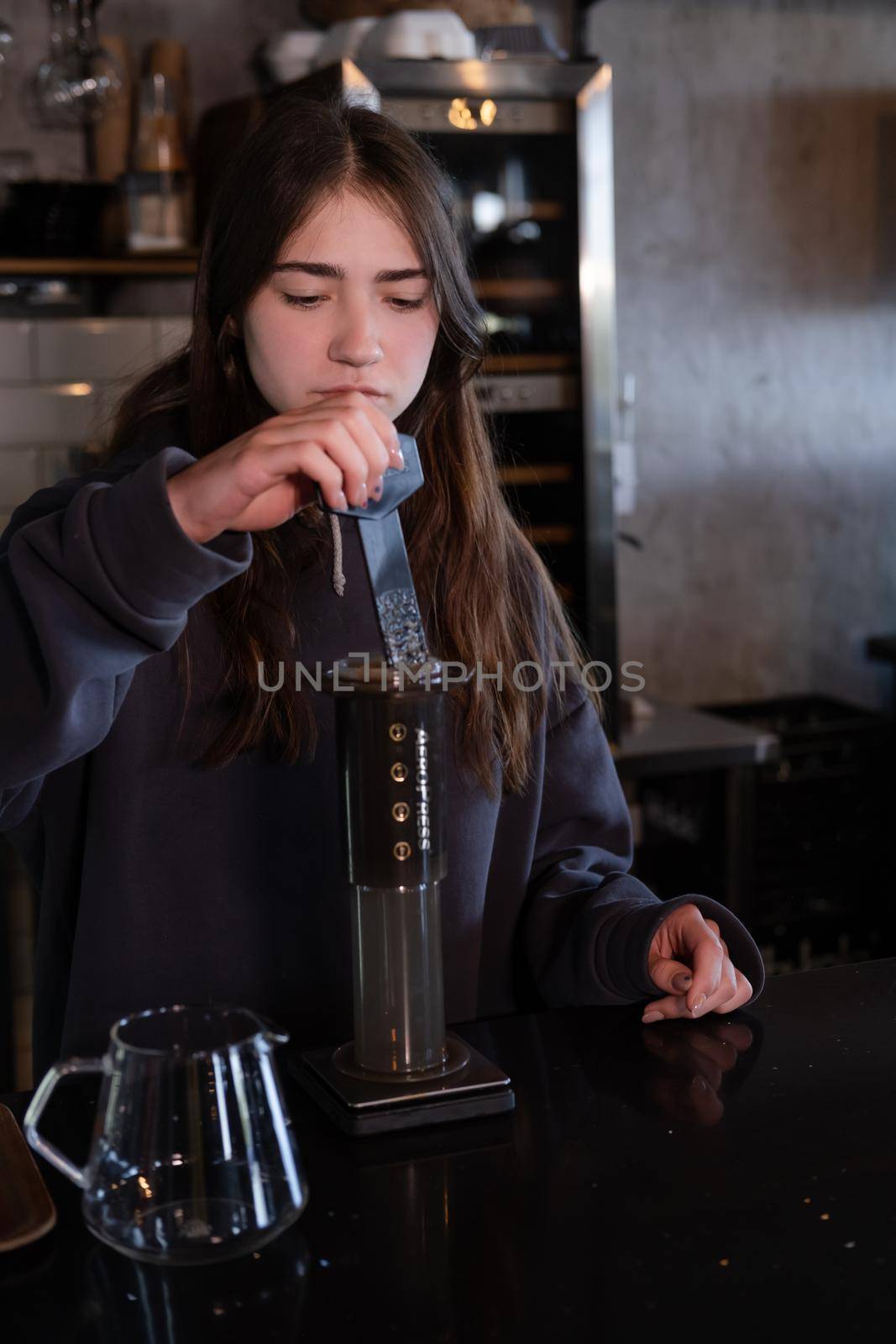 pretty brunette girl making aeropress coffee in modern coffee shop.