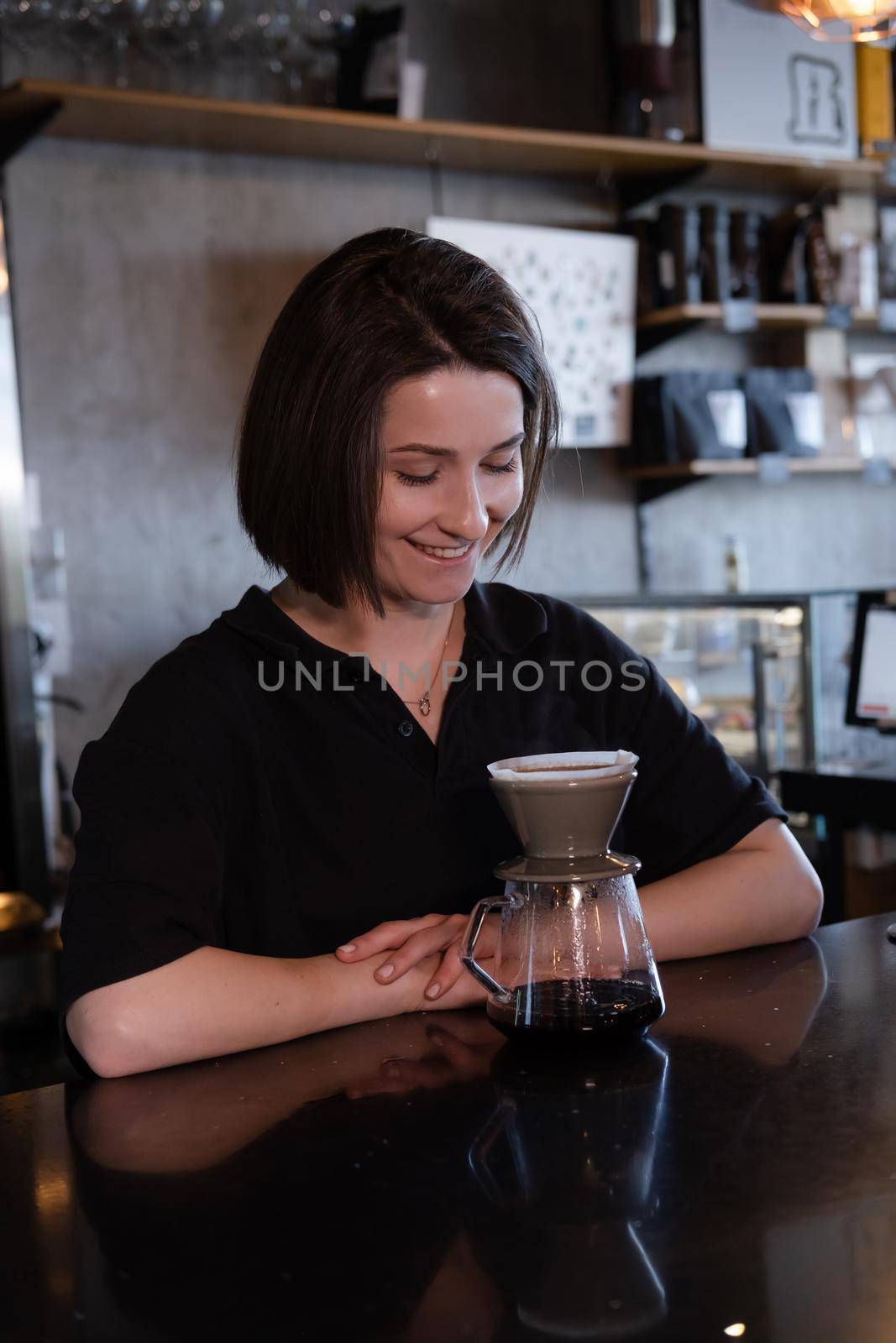 charming brunette woman barista making filter coffee in coffee shop. brewing coffee in cafe.