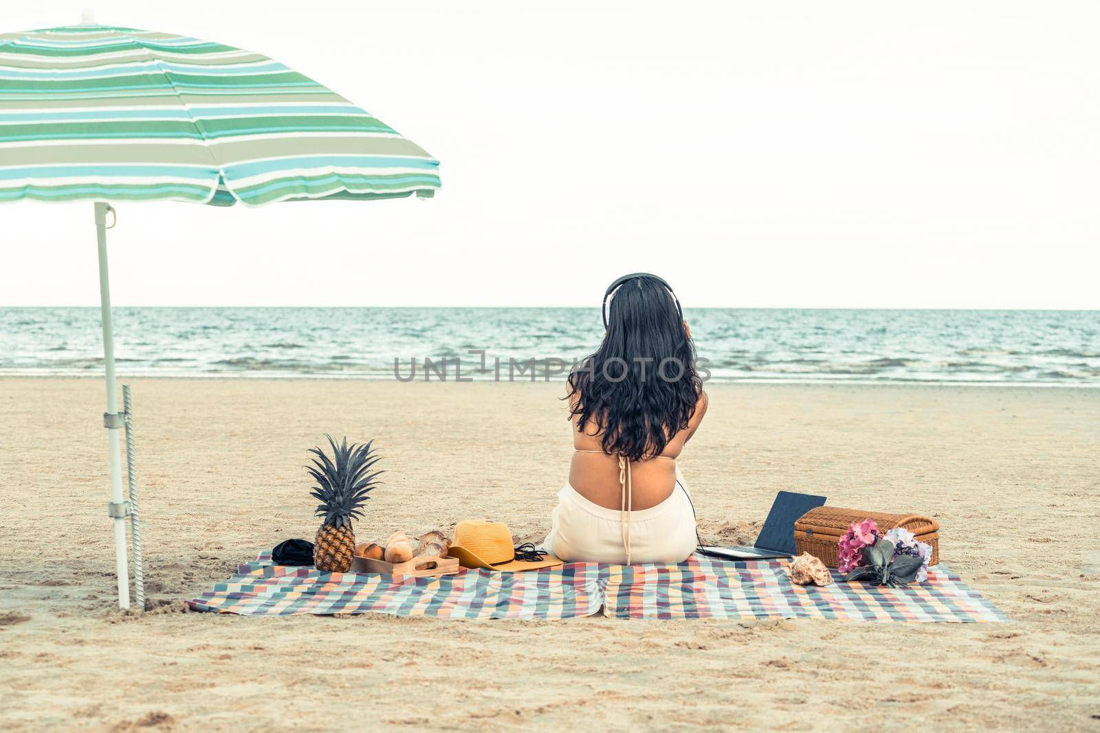 Woman in bikini is on vacation sitting on the beach in summer. Tropical beach travel lifestyle.
