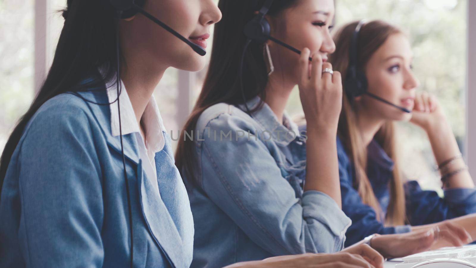 Customer support agent or call center with headset works on desktop computer while supporting the customer on phone call. Operator service business representative concept.