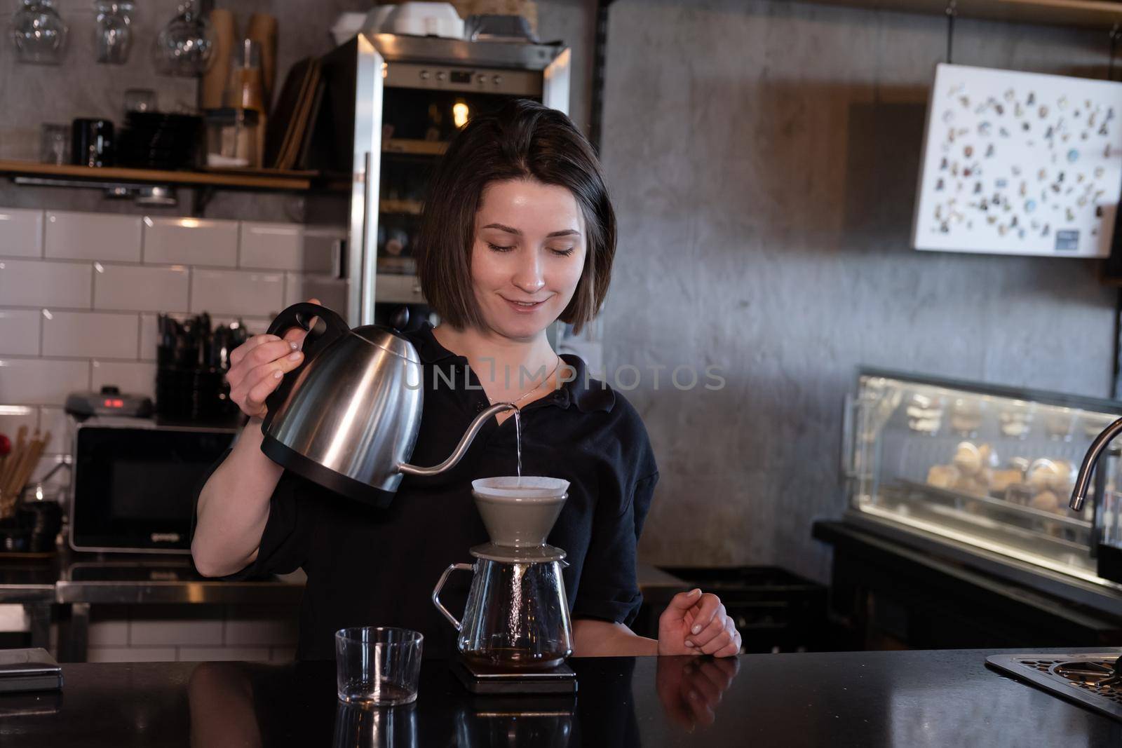 charming brunette woman barista making filter coffee in coffee shop. brewing coffee in cafe.