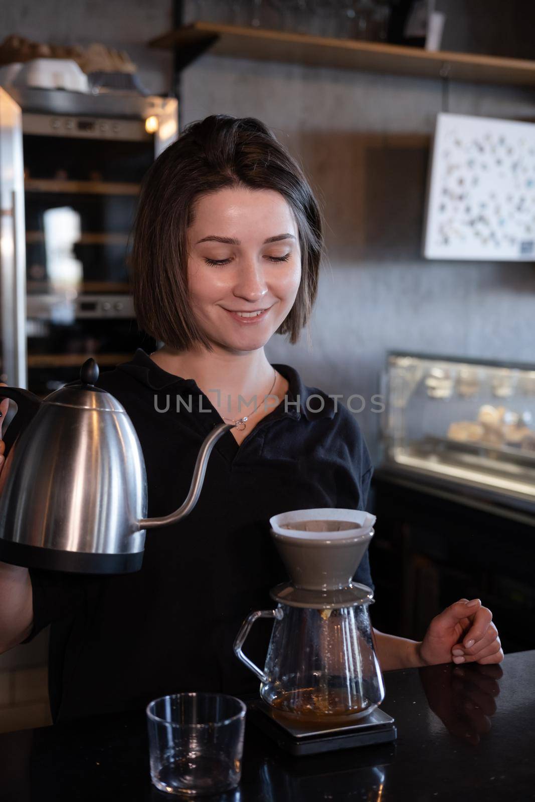 charming brunette woman barista making filter coffee in coffee shop. brewing coffee in cafe by oliavesna