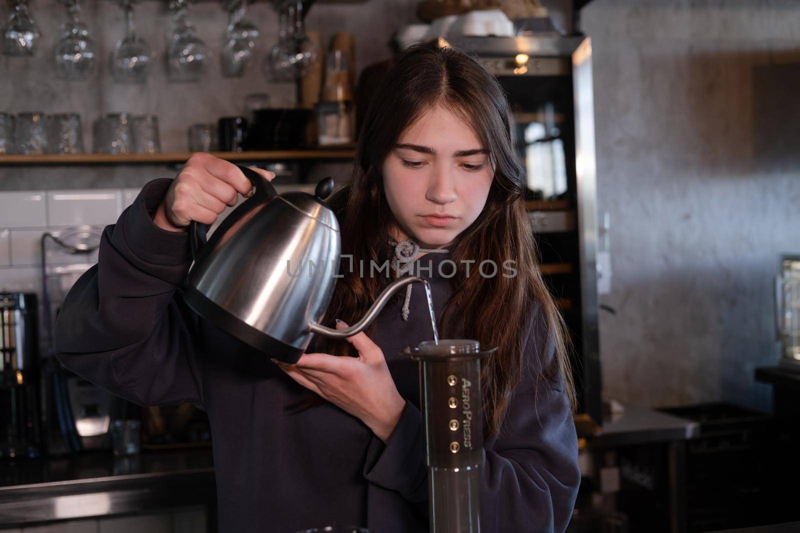 pretty brunette girl making aeropress coffee in modern coffee shop.