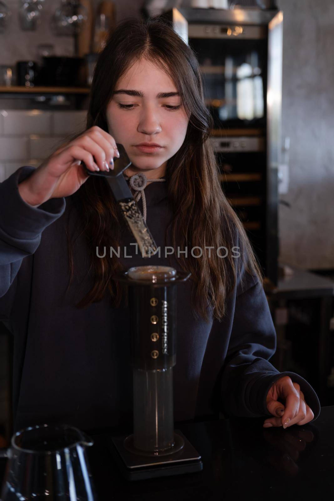 pretty brunette girl making aeropress coffee in modern coffee shop.