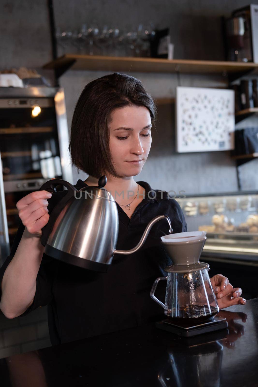 charming brunette woman barista making filter coffee in coffee shop. brewing coffee in cafe.