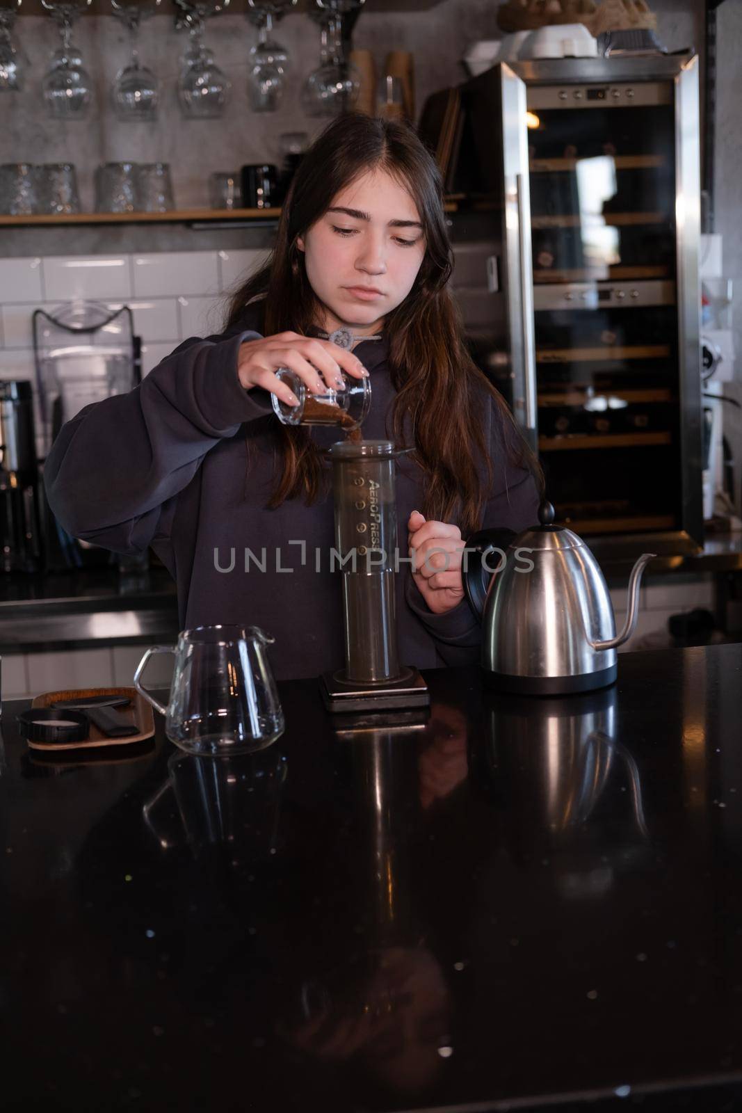 pretty brunette girl making aeropress coffee in modern coffee shop.